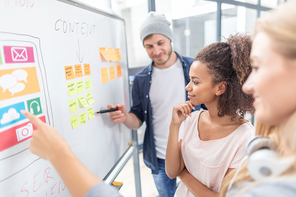 Group of people looking at white board in meeting