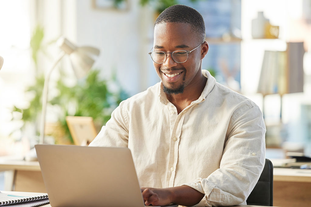 Young man smiling looking at a computer