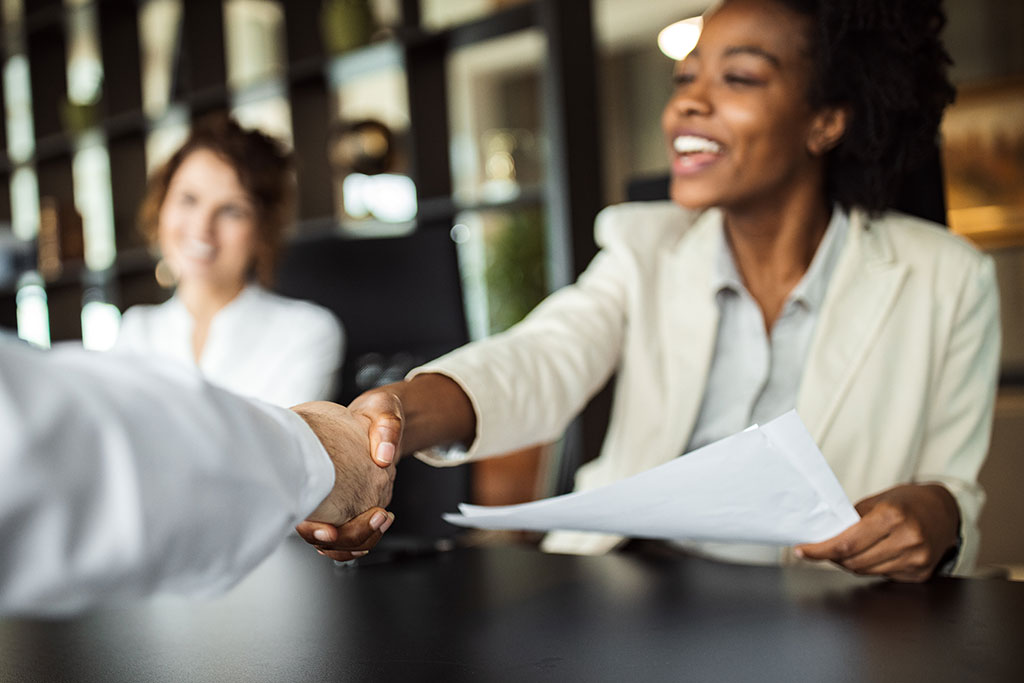 Women at work shaking hands with someone from across a table