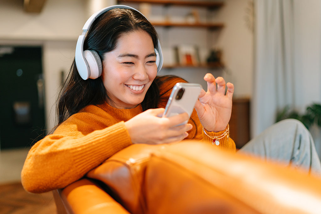 Lady on couch wearing headphones and on phone