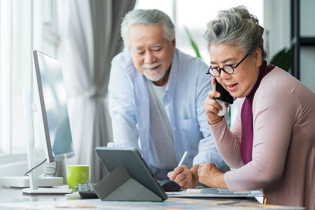 Elderly couple talking on phone and on computer