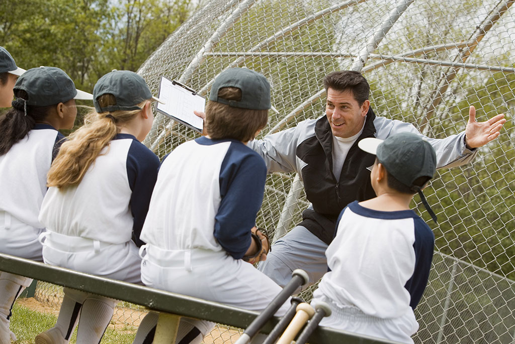 Coach coaching little league baseball team