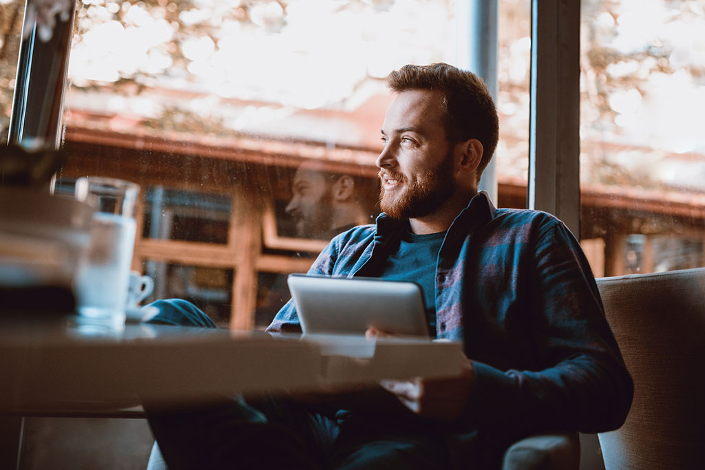 Man at coffee shop on tablet