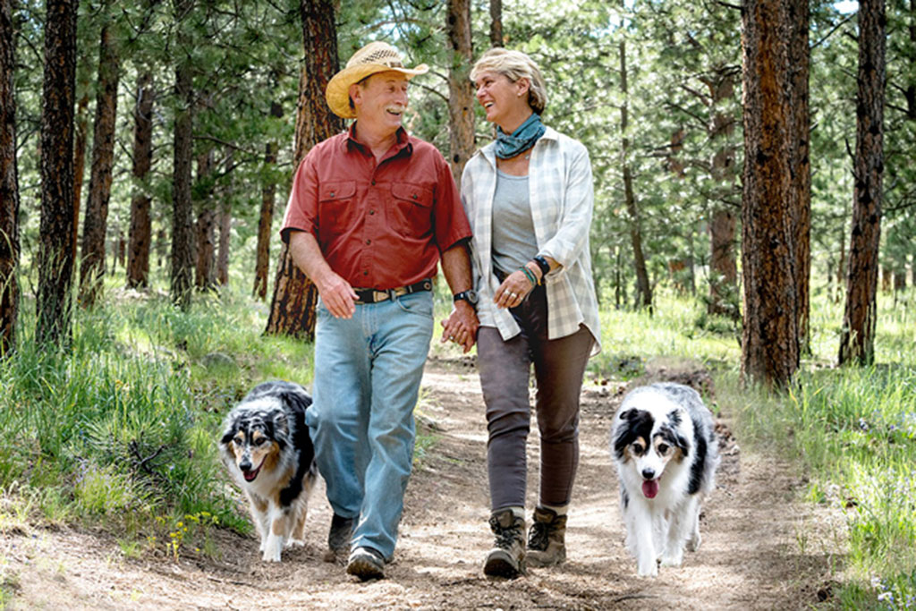 Older couple walking on trail with dogs