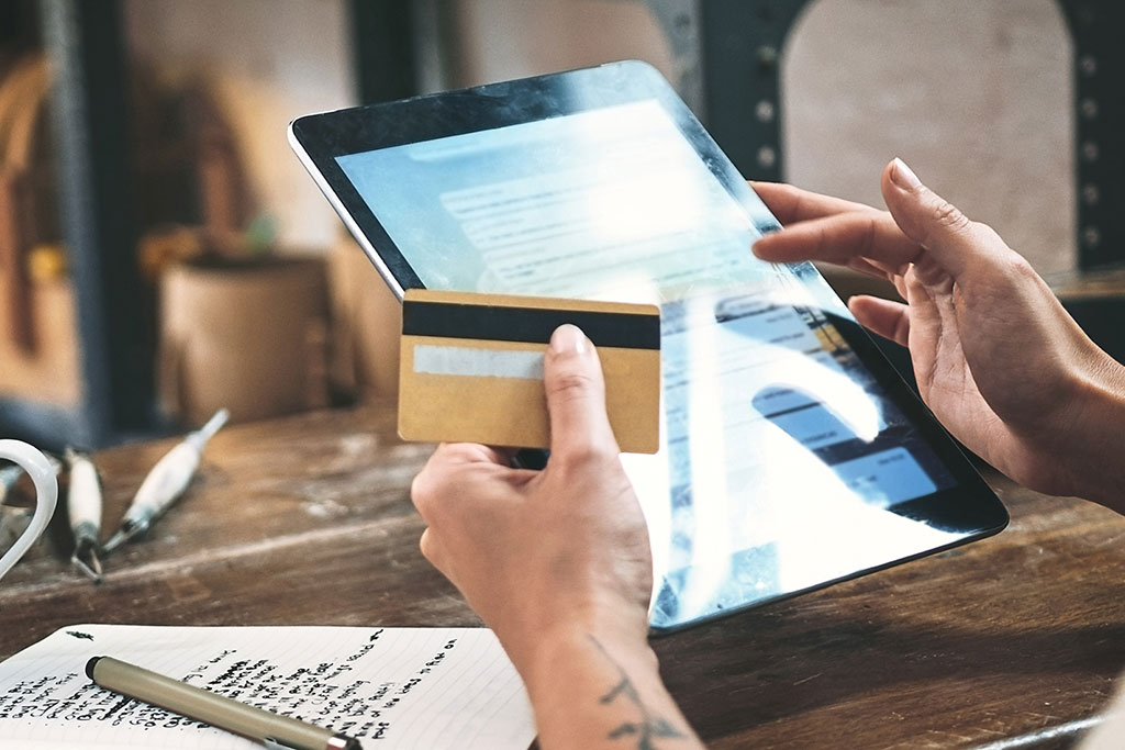 Person putting credit card information in tablet to pay