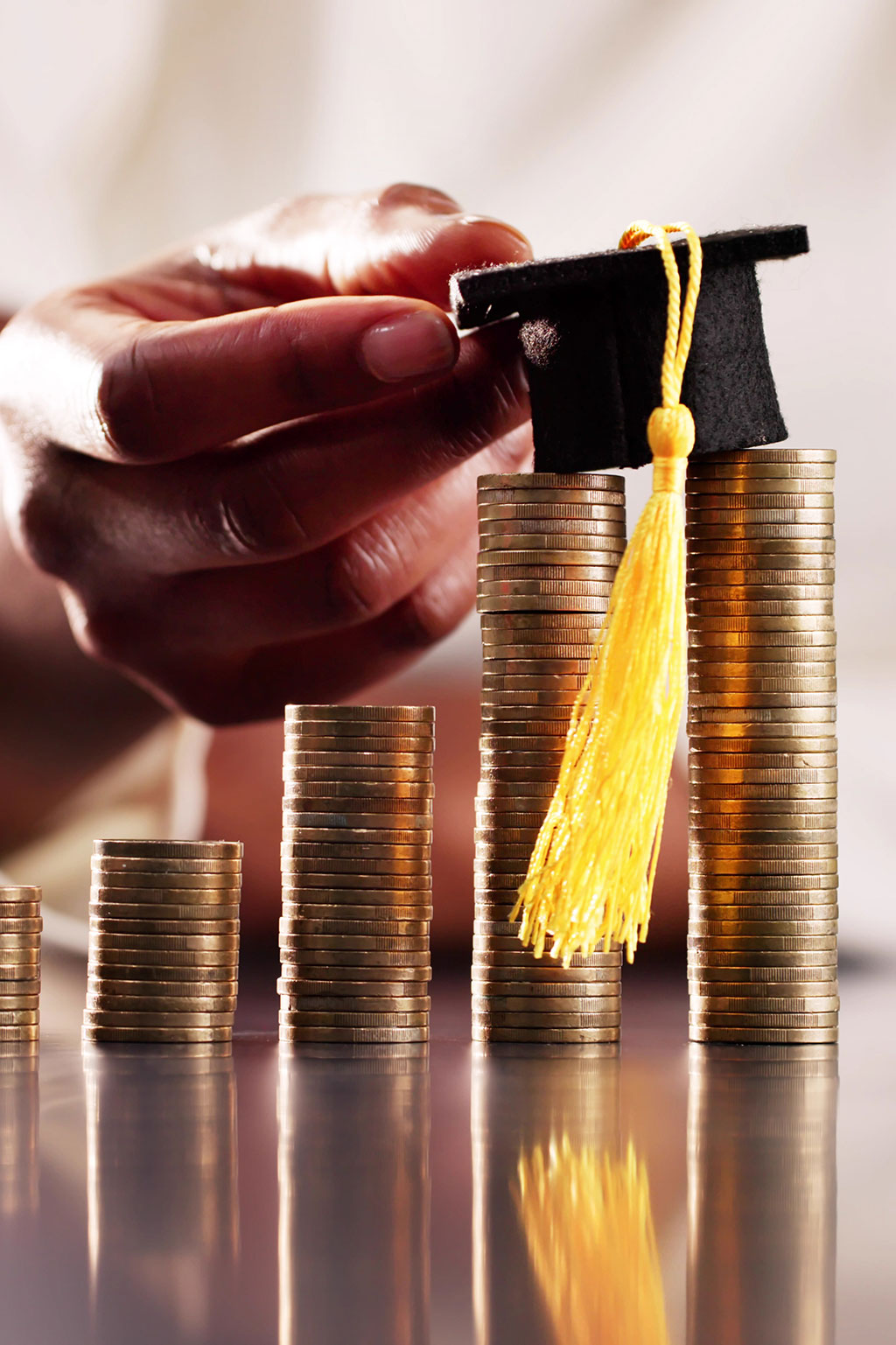 Coins stacking up with graduation cap on top